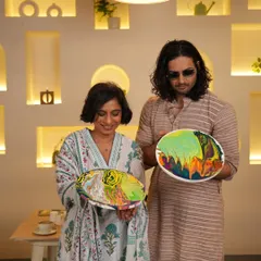 Sucharita and Ali showing off their finished fluid art pieces. Each one is a unique swirl of colors, reflecting their creative expression during the session.