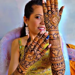 Here is a radiant bride on her engagement day. Her mehendi is a full-coverage design with geometric grids, floral elements, and personalized initials on each hand.