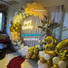 This view shows the gold and silver ring arch with a path of red rose petals leading to it, adding an extra touch of romance to the birthday celebration. Large "24" foil balloons mark the age.