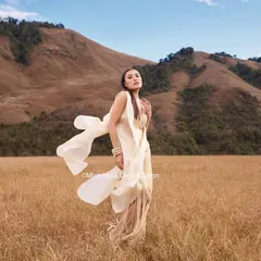 A breathtaking shot from the Femina Miss India shoot, with a model in a flowing white dress against a mountain backdrop. Her hair is styled in a soft updo to create a sense of movement and grace.