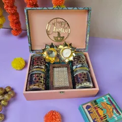 A beautiful wooden Diwali hamper containing jars of nuts, a photo frame, and decorative lotus diyas. The box itself is a keepsake.