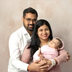 The complete family, smiling and happy. This portrait shows the joy of new parents as they hold their baby, creating a memory that will be treasured for years.