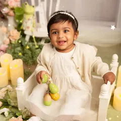 A happy moment with a favorite toy. This toddler portrait captures the baby's sweet smile as she plays in a beautifully arranged studio set.
