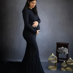 A classic and elegant solo maternity portrait. The mom-to-be wears a simple black gown and a delicate tiara, creating a look of regal grace.