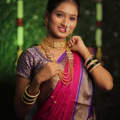 A happy bride adjusting her layered gold necklaces. This shot highlights the intricate details of traditional Maharashtrian bridal jewelry and the soft, glowing makeup that complements it.