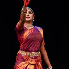 A powerful moment from a solo performance, with the dancer's arm raised in a gesture of command or declaration. The red-painted hands add to the dramatic effect.