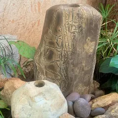 This fountain combines a carved stone pillar with natural rocks and water-loving plants like peace lilies to create a serene corner.