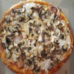 A gluten-free pizza with a generous topping of caramelized onions, mushrooms, and my special in-house vegan cheese.