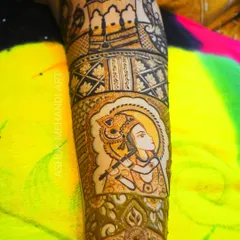 A full-arm design featuring a prominent portrait of Lord Krishna. The artwork is framed beautifully and sits above intricate jaal and floral patterns.