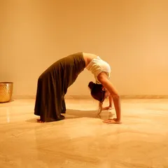 A deep backbend in the wheel pose. This is an advanced yoga posture that demonstrates incredible flexibility and strength, essential for a dancer's body.