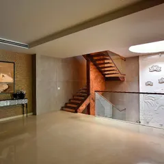 In this Delhi farmhouse, the staircase landing is a serene space. A circular skylight washes the area in natural light, highlighting a stunning white bas-relief panel that depicts sacred motifs, turning a simple transition space into a moment of art.