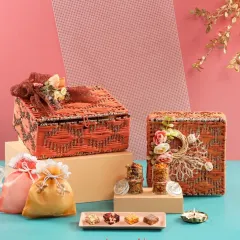 A set of our handcrafted jute hampers in a warm orange tone. These eco-friendly boxes are decorated with floral arrangements and potlis, making them a sustainable and beautiful gift.