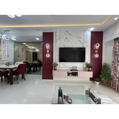 A closer look at the statement TV wall, which combines a marble-finish backdrop with rich burgundy panels and bespoke wall sconces. This feature serves as the focal point of the room.