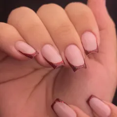 Simple, chic, and perfect for any occasion. This is a modern French manicure with a deep, curved tip using a beautiful red glitter polish on clean, square-shaped nails.