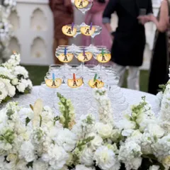 A beautiful champagne tower set amidst a stunning floral arrangement. We personalize the experience with custom initial tags, making the toast a truly special and photogenic moment.