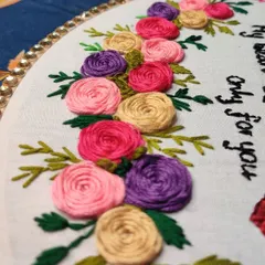 A detail shot of another custom embroidery piece with a heartfelt quote, "my heart beats only for you," surrounded by colorful hand-stitched roses.