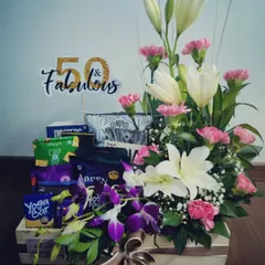 This 50th-anniversary hamper is a masterpiece of fresh flowers. It combines white lilies, pink carnations, and purple orchids with a selection of healthy snacks for a truly sophisticated gift.