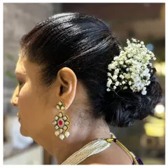 A classic low bun hairstyle, elegantly decorated with a cluster of baby's breath. This is a timeless and sophisticated choice for any formal occasion.
