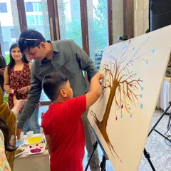 Guiding a young guest as he adds his contribution to the thumbprint tree. These moments of shared creation are truly special.