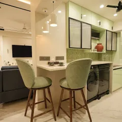 A cozy breakfast counter connects this kitchen to the living area. The setup includes two comfortable sage green bar stools, perfect for quick meals or a morning cup of tea.