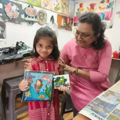 One of our instructors with a young student, proudly showing off the aquarium frame and dinosaur tile she made. We love celebrating every child's unique creations.