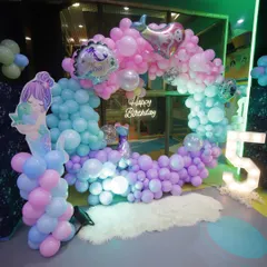 An enchanting underwater world for a mermaid-themed 5th birthday. This circular balloon arch creates a perfect photo booth area, complete with a neon sign and themed character cutouts.