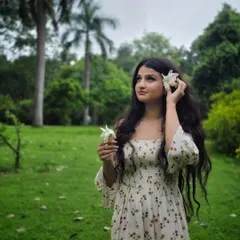A dreamy, whimsical portrait in the park. Using a flower as a prop adds a soft, natural element to the shot, perfectly matching the green surroundings.