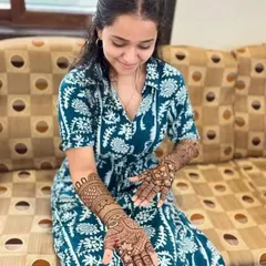 A happy client admiring her full-arm mehandi. The design is intricate and the stain has come out beautifully dark.