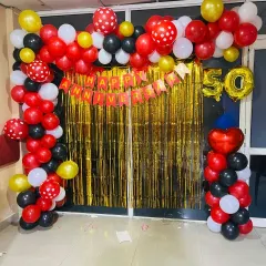 A golden jubilee celebration for a 50th anniversary. I designed this backdrop with a red, black, white, and gold balloon arch over a shimmering gold curtain. The large '50' foil balloons make it clear what milestone is being celebrated.