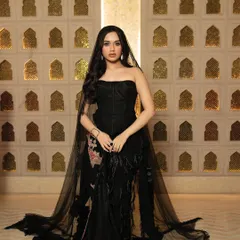 A full-length shot of Jannat Zubair for GlobalSpa, showcasing the entire black gown with its flowing train against an ornate backdrop.