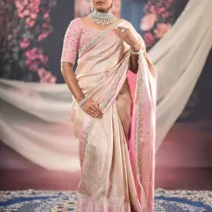 A full-length shot showing the complete ensemble. The soft glam makeup perfectly complements the elegant pink and cream saree.