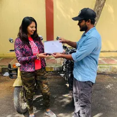 The official handover. A student receives her Certificate of Accomplishment, marking the successful completion of her beginner motorcycle training.