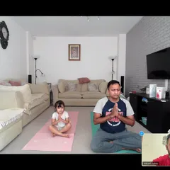 Even from afar, families can connect through yoga. Here, a father and his young daughter join our online session, finding peace and practicing mindfulness together from their home.