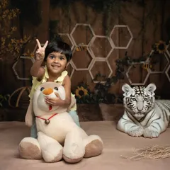 Two years old and full of life! This fun shot from a jungle-themed studio session captures a toddler's excitement as she poses with her stuffed animal friends.