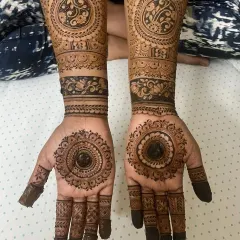 A beautiful bridal mehendi for Anushiya, set against her vibrant pink saree. The design features bold mandalas on the palm and detailed cuff work on the arms, showing how the henna complements the entire bridal look.