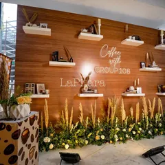 We created this beautiful photo wall with a wood-paneled backdrop and floating shelves. Each shelf was styled with coffee-themed decor, books, and candles, providing an elegant and on-theme photo opportunity for guests.