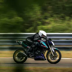 Poojita AK, one of our rising stars, blurs past the trackside scenery on her TVS RTR 200. This panning shot captures the sheer speed she carried to secure a double podium finish at the INMRC 2025 season opener.