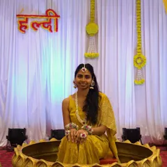 A full view of a bride at her Haldi ceremony, seated in a decorative lotus-themed seat. She is wearing a complete handmade floral jewellery set that I designed for her special day.