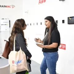 A member of our team in a detailed discussion with a visitor about our wellness solutions. You can see the IQAir tote bag, a brand synonymous with quality air, which reflects the shared interest in creating healthier indoor environments.