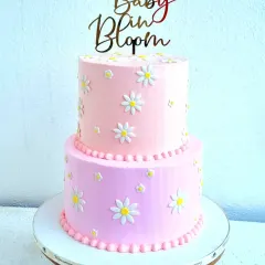 A two-tiered "Baby in Bloom" shower cake with a soft pink buttercream finish. I show how to make these simple but perfect daisy flowers from fondant and how to pipe a neat pearl border.