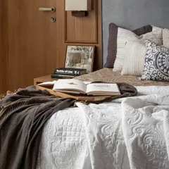 Wooden accents, from wardrobe shutters to doors, infuse this bedroom with warmth. The rest of the space is intentionally understated, with tone-on-tone mouldings and soft neutral decor allowing the natural textures to quietly take the lead.