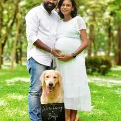 "We're having a baby!" A classic announcement shot that beautifully includes the family dog. This outdoor maternity session in a lush green park highlights the joy and anticipation of the whole family.