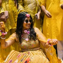 All smiles during the Haldi function. The bride, adorned with floral jewelry, is ready for the fun to begin.