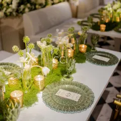 A closer look at our elegant tablescape design. Textured green glass plates and goblets are paired with fresh moss and white tulips, creating a natural yet luxurious setting that makes every guest feel special.
