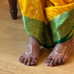 An intricate bridal foot design with jhumka (earring) motifs, perfectly complementing a traditional bridal outfit.
