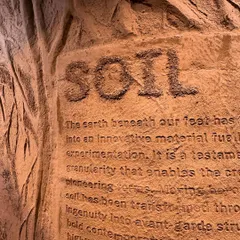 A close-up of our 'Soil' installation, where the word itself is carved into the earthen material. This detail highlights the granular texture and raw essence of soil as a medium for creation and storytelling.