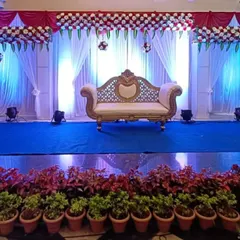 An engagement stage setup with a clean, wide design. This features a red and white floral arrangement across the top, white drapes, and dramatic blue uplighting for a modern feel.