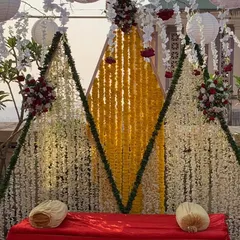 A unique and modern Haldi backdrop with a geometric design. We used curtains of white and yellow flowers to create three distinct panels, offering a contemporary twist on traditional floral decor.