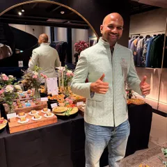 A happy client trying on a mint green bandhgala jacket. This modern Indian groom styling is perfect for a sangeet or reception, pairing effortlessly with jeans for a smart, contemporary look.