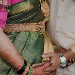 A close-up shot focusing on the intricate silver waist belt and the way it complements the green and pink saree, a perfect accessory for a maternity celebration.